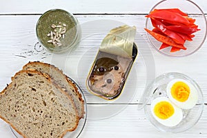 Cod liver in a tin  on white wooden table, flat lay.