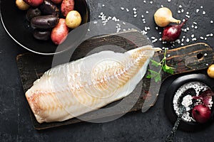 Cod white fish potatoes dish ingredients for healthy comfortable home food. Raw white fish fillet in a baking dish on a