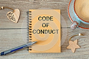 CODE OF CONDUCT - inscription on a notebook and cup with coffee