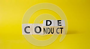 Code of conduct symbol. Turned cubes with words Conduct abd Code. Beautiful yellow background. Business and Code of conduct