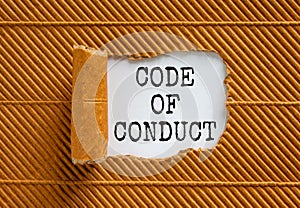 Code of conduct symbol. Words `Code of conduct` appearing behind torn brown paper. Beautiful brown background. Business, code of