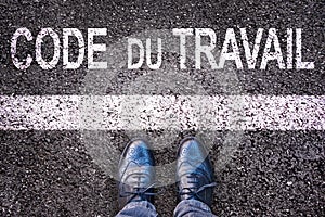 Code du travail meaning labor code in French written on an asphalt road background with legs