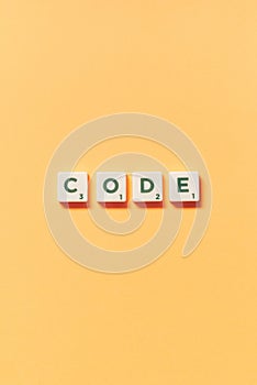 Code formed of scrabble blocks on yellow background.