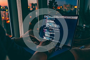 The code on the laptop screen at night. Software development. Developer is programming a code script late at night
