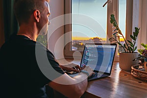 The code on the laptop screen at night. Software development. Developer is programming a code script late at night