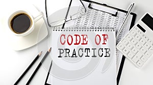 CODE OF PRACTICE text on the paper with calculator, notepad, coffee ,pen with graph