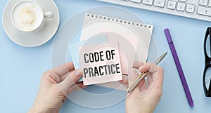 CODE OF PRACTICE text on paper with calculator, notepad, coffee