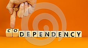 Codependency or dependency symbol. Concept words Codependency and dependency on wooden cubes. Psychologist hand. Beautiful orange