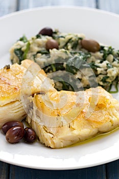 Codfish with bread and spinach on white plate