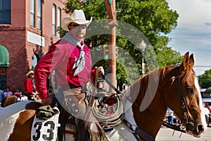 Cody, Wyoming, USA - Cowboy with bright red shirt riding on the Independence Day Parade