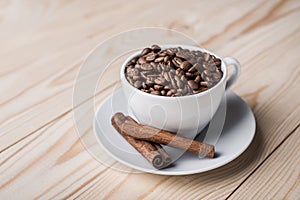 Coffe beans in white cup with cinamone.
