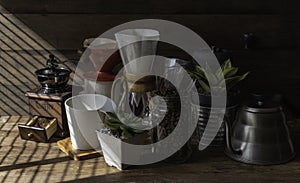 Coffe drip set with,roasted beans,kettle,grinder,white cup and flower pot on wood table and background