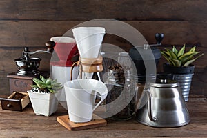 Coffe drip set with,roasted beans,kettle,grinder,white cup and flower pot on wood table and background