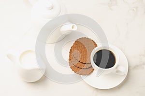 Coffe white cup with cookies and milk/Coffe white cup with cookies and milk on white marble background. Top view