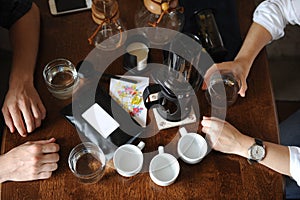 Coffee accessories on a dark wooden table with hands