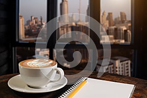 Coffee aroma in cup breakfast morning drink on wooden table in cafe shop with note pad and newspaper background