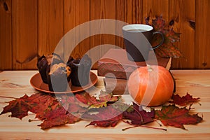 Coffee, autumn maple leaves, pumpkin, books and vanilla muffins on wooden table