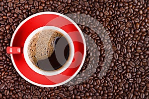 Coffee background of hot black coffee in red cup on roasted arabica coffee beans background