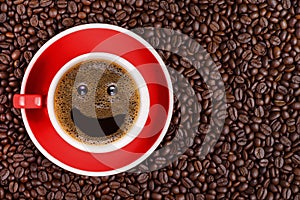 Coffee background of hot black coffee with smile bubble in red cup on roasted arabica coffee beans background