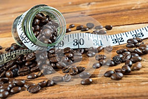 Coffee bean in glass bottle with tape measure on wooden background