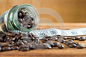 Coffee bean in glass bottle with tape measure on wooden background