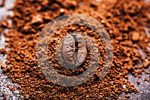 Coffee bean on heap of grinded coffee