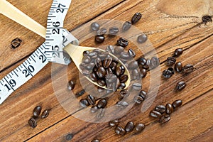 Coffee bean on wooden spoon, tape measure on wooden background