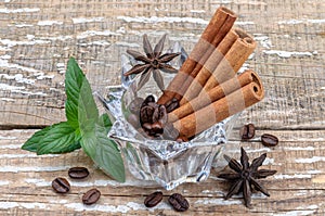 Coffee beans and aromatic spices on a wooden background in a glass vase