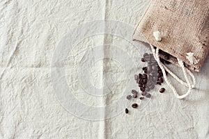 Coffee beans in bag on linen tablecloth