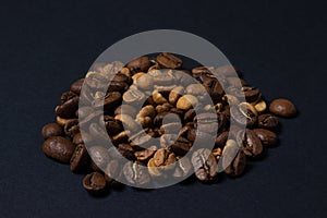 Coffee beans on a black background. Coffee beans of different roasts in one pile.