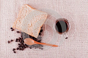 Coffee beans and bread and a glass of espresso.