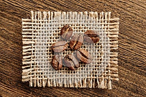 Coffee beans on a burlap flap close-up on a background of rough wood