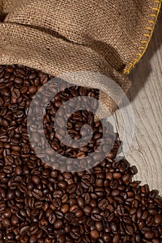 Coffee beans in burlap sack against dark wood
