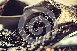 Coffee beans in burlap sack on old wooden table