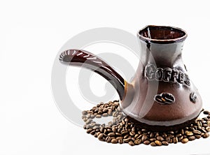 Coffee beans and ceramic cezve with an inscription of coffee on a white background