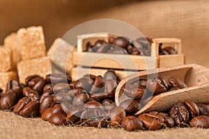 Coffee beans and cinnamon on a background of burlap. Roasted coffee beans background close up. Coffee beans pile from top with