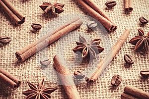 Coffee beans and cinnamon sticks with anise stars organized separately on sackcloth