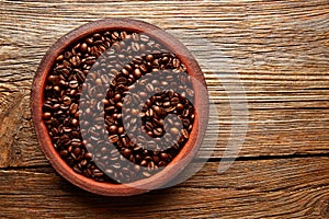 Coffee beans in a clay dish texture on wood