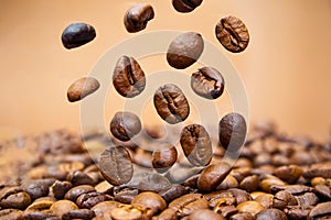 Coffee beans close up falling on pile against brown background