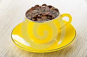 Coffee beans in coffecup on saucer on wooden table