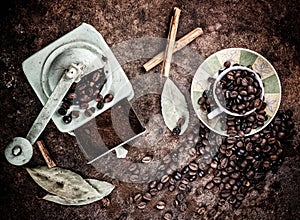 Coffee beans coming out of cup with grinder background