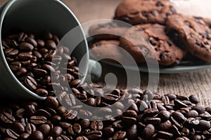 Coffee beans crumbled with a cup, in the background a plate of cookies