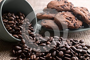 Coffee beans crumbled with a cup, in the background a plate of cookies photo