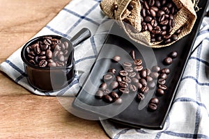 Coffee beans in cup and bag on wooden background