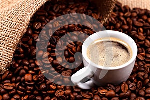 Coffee beans and a cup in burlap sack