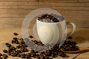 the coffee beans and cup of coffee on sack with spoon onwooden t