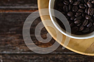 Coffee beans in a cup on wooden background.