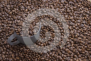 Coffee beans in dark cup on mixed coffee beans background