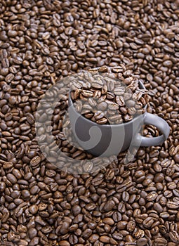Coffee beans in dark cup on mixed coffee beans background
