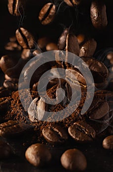 Coffee beans falling on ground coffee on the table. The aroma of roasted arabica and robusna coffee beans. Dark background and